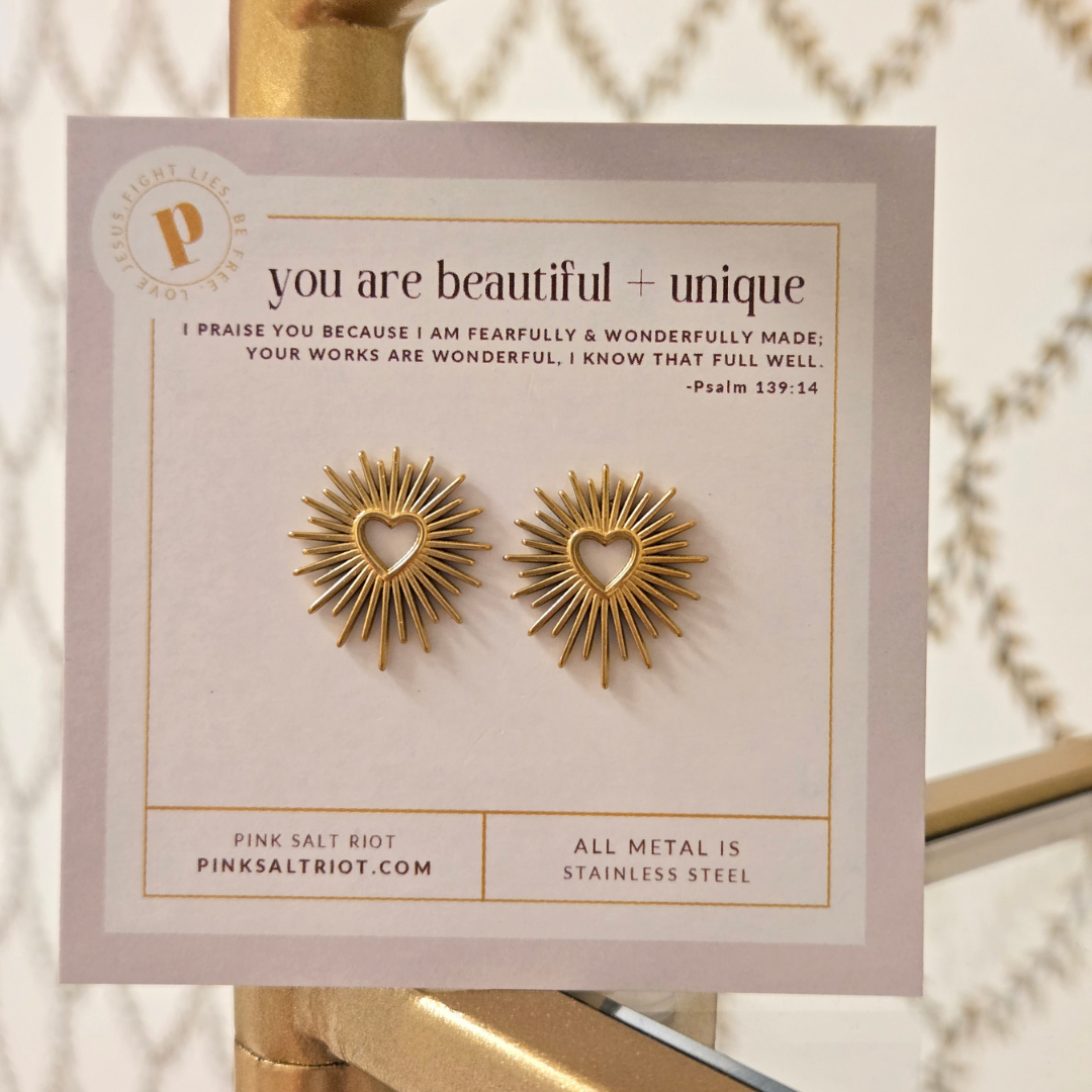 Gold heart-shaped earrings on a Pink Salt Riot branded card with motivational quote.
