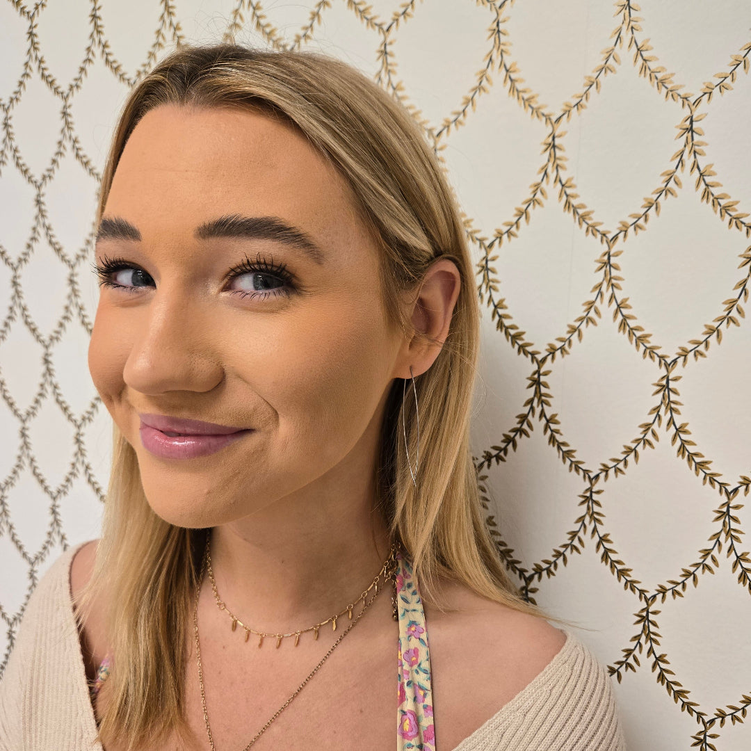 Woman wearing Pink Salt Riot Christian minimalist earrings with long blonde hair and neutral outfit